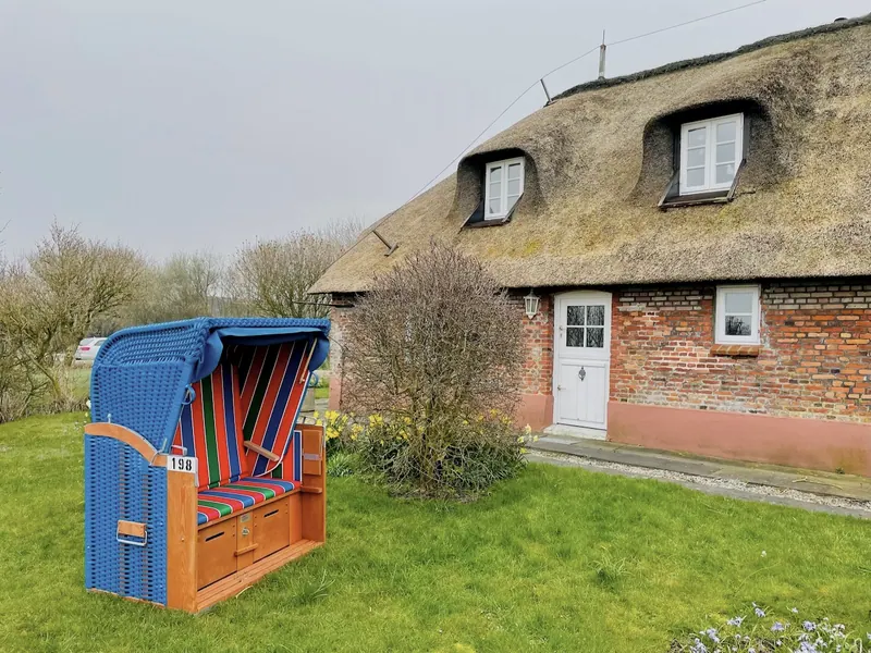 Blauer Strandkorb im Garten hinter dem Reetdachhaus