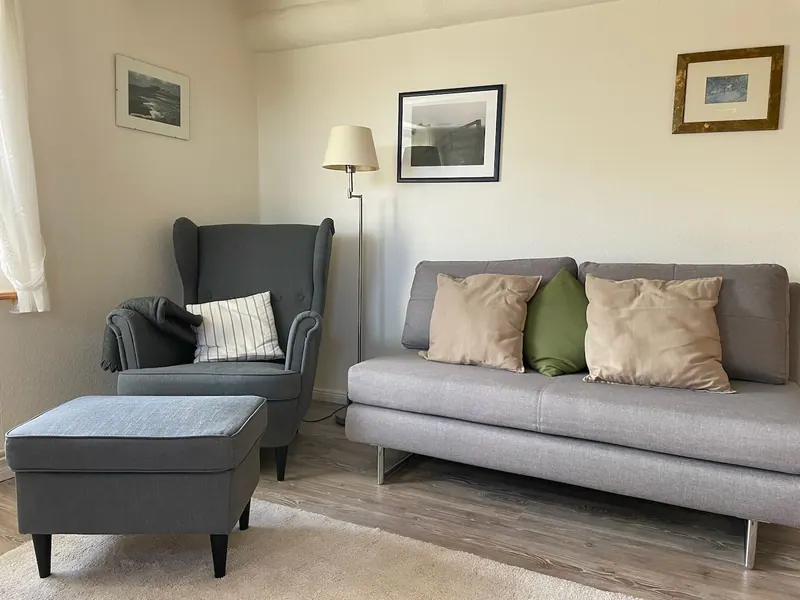 Graues Sofa und gemütlicher Lesesessel in der Ferienwohnung Norderoog